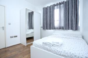 um quarto branco com um espelho e uma cama em Gorgeous 2 bedroom 2 bathroom Woolwich em Woolwich