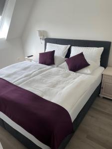 Cama grande con sábanas y almohadas moradas y blancas en Seaside-Amrum-13 en Norddorf