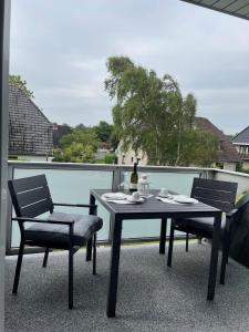 a table and chairs on a balcony with a bottle of wine at Seaside-Amrum-13 in Norddorf