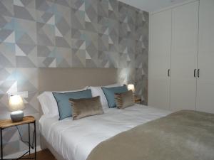 1 dormitorio con 1 cama blanca grande con almohadas azules en Mi Refugio, en Monforte de Lemos