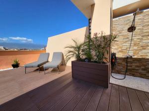 a wooden deck with two chairs and a plant at MEDANO4YOU Kevin's Penthouse in El Médano