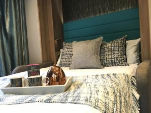 a bed with a blue headboard with a tray on it at P72 - Swift Pod with Hot Tub in Bangor