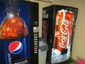 un distributore automatico di coca cola accanto a una bottiglia di coca di Super 8 by Wyndham Mitchell a Mitchell