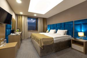 舒门苏门大酒店的酒店房间，配有一张大床和一台电视