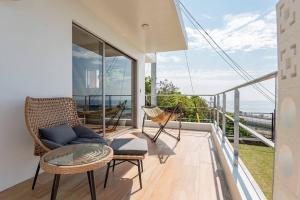 a balcony with a couch and a table and chairs at villa modama in Nanjo