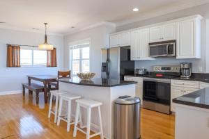 una cocina con armarios blancos y una mesa con taburetes en Paradise Island Ocean Front, en Carolina Beach