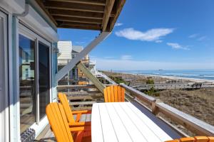 balcón con mesa y sillas y la playa en Paradise Island Ocean Front, en Carolina Beach