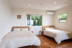 Duas camas num quarto com paredes brancas e pisos em madeira em villa modama em Nanjo