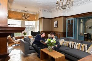 a man and woman sitting in a living room at Escape Boutique B&B in Llandudno