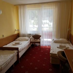 クリニツァ・ズドルイにあるGeovita Krynica-Zdrojのベッド2台、椅子、窓が備わる客室です。