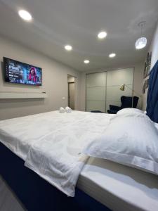 - une chambre avec un grand lit blanc et une télévision à écran plat dans l'établissement Krivenko 49 Str by Slissenko Inn, à Pavlodar
