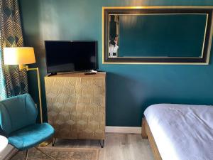 a bedroom with a bed and a tv and a chair at The Hole In The Wall in Little Wilbraham