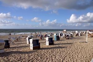una playa con muchas sillas de playa y el océano en Ferienwohnung Landhaus, en Maasbüll