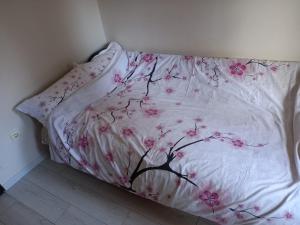 un letto con una coperta bianca con fiori rosa di Sofia Apartment a Surčin