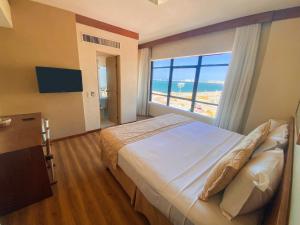 a bedroom with a bed with a view of the beach at Magna Praia Hotel in Fortaleza +24 photos