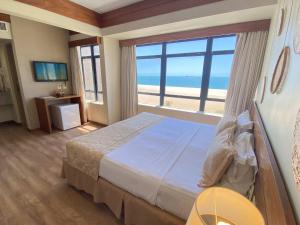 a bedroom with a bed with a view of the beach at Magna Praia Hotel in Fortaleza