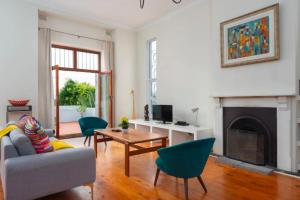 a living room with a couch and chairs and a fireplace at Kloof Avenue 5 in Cape Town