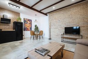 ein Wohnzimmer mit einem TV und einer Ziegelwand in der Unterkunft Magno Apartments Requena in Sevilla