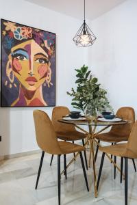 ein Esszimmer mit einem Tisch und Stühlen mit einem Gemälde in der Unterkunft Magno Apartments Requena in Sevilla