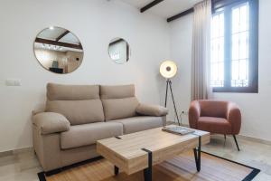 ein Wohnzimmer mit einem Sofa und einem Tisch in der Unterkunft Magno Apartments Requena in Sevilla
