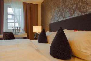 a hotel room with a bed with black pillows at Landhotel Zum Kronprinzen in Oberwesel