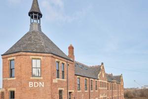 un antiguo edificio de ladrillo con una torre de reloj en la parte superior en No 5 at Simpson Street Apartments Sunderland, en Sunderland