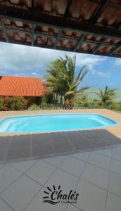 a large blue swimming pool in front of a house at Chalé com piscina privada vista mar-Zumbi-RN in Rio do Fogo