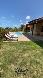 a group of lawn chairs sitting next to a pool at Chalé com piscina privada vista mar-Zumbi-RN in Rio do Fogo