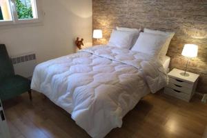 a large white bed in a bedroom with a brick wall at Blagnac : appartement T2 avec jardin, parking et climatisation in Blagnac