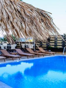 um grupo de cadeiras debaixo de um guarda-sol de palha ao lado de uma piscina em Mati Hotel em Mati