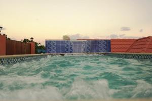 a swimming pool with blue chairs in the water at Royal Vybez Vacation Homes in Spanish Town