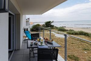 un tavolo su un balcone con vista sulla spiaggia di Superbe appartement neuf face plage sur l ile de Noirmoutier a La Guérinière