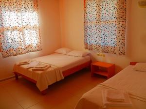 a room with two beds and two windows with curtains at Cirali Irmak Hotel in Cıralı