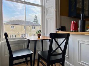 uma mesa e duas cadeiras numa cozinha com uma janela em The Georgian Manor Apartment - Central Frome em Frome