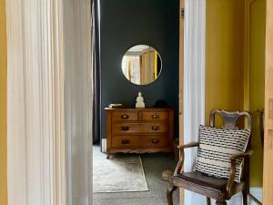 a room with a mirror and a chair and a dresser at The Georgian Manor Apartment - Central Frome in Frome