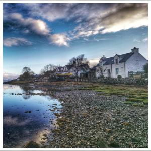 a group of houses next to a body of water at Tidal Cottage On The Shore Isle of Skye in Breakish