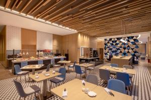 青島市にあるHoliday Inn Express Qingdao Jinshui, an IHG Hotelのテーブルと椅子のあるレストラン、キッチンが備わります。