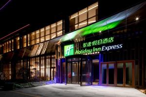 a building with a neon sign on the side of it at Holiday Inn Express Qingdao Jinshui, an IHG Hotel in Qingdao