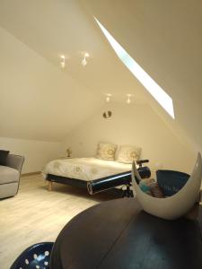 a attic room with a bed and a table at Le Bonheur En Bretagne in Rouillac