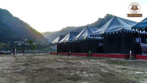 瑞诗凯诗Riverside Swiss Camps "Adventure Bear Buddies"的山 ⁇ 背面的一排黑色帐篷