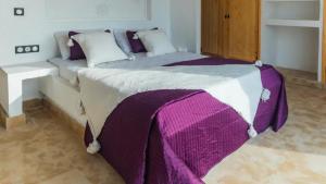 a bed with a purple and white blanket on it at Villa avec piscine Asilah, terrain de foot privative in Asilah