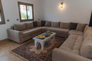 a living room with a couch and a coffee table at Villa avec piscine Asilah, terrain de foot privative in Asilah