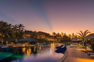 a pool at a resort with a rainbow in the sky at Carmel Charme Resort in Jacaúna