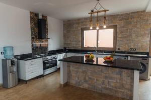 a large kitchen with a island with fruits on it at Villa avec piscine Asilah, terrain de foot privative in Asilah
