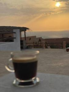 a cup of coffee sitting on a table near the ocean at Villa avec piscine Asilah, terrain de foot privative in Asilah