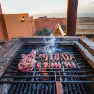 a bunch of meat cooking on a grill at Villa avec piscine Asilah, terrain de foot privative in Asilah