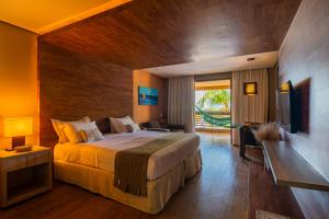 1 dormitorio con 1 cama grande y TV en Carmel Charme Resort en Aquiraz