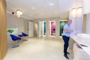 a woman standing at a sink in a bathroom at Quality Hotel Olavsgaard in Skjetten