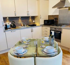 uma cozinha com uma mesa de vidro com copos de vinho em Riverside View Apartment in Balloch, Loch Lomond em Balloch