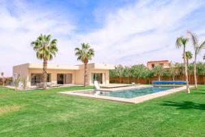 a villa with a swimming pool and palm trees at Villa des sœurs bradaa in Marrakesh